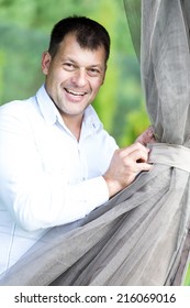 Happy Smiling Man Steward Fixing Gazebo Curtains During Party Entertainment