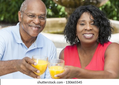 A happy, smiling man and woman senior African American couple outside drinking orange juice