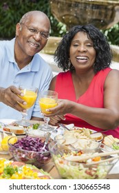 A Happy, Smiling Man And Woman Senior African American Couple Eating Healthy Food At A Picnic Table Outside