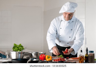 Happy smiling mature chef preparing a meal with various vegetables - Powered by Shutterstock