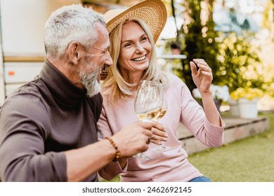 Happy smiling mature couple having romantic picnic and drinking wine in the garden. Quality time - love language. Celebration of anniversary special event together - Powered by Shutterstock