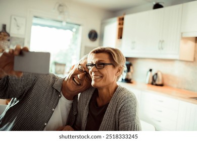 Happy smiling mature couple taking selfie in kitchen - Powered by Shutterstock