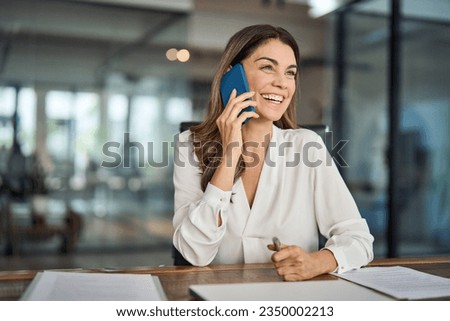 Happy smiling mature mid aged business woman, cheerful 40 years old professional lady executive manager or entrepreneur talking on phone making business call on cellphone at work in office.