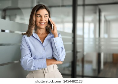 Happy smiling mature middle aged business woman, older professional lady executive manager leader talking on phone making business call on cellphone at work communicating by telephone in office. - Powered by Shutterstock