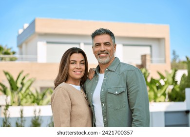 Happy smiling mature older family couple new property buyers modern villa owners standing outside house, affectionate middle aged man and woman in love hugging outdoor. Portrait. Vacation home rentals - Powered by Shutterstock