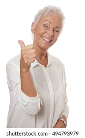 happy smiling mature woman in her sixties with trendy white short hair making thumbs up hand sign
