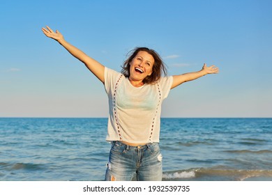 Happy smiling mature woman on the sea beach, positive female with arms raised up. Happiness, joy, relaxation, emotions, middle-aged people - Powered by Shutterstock