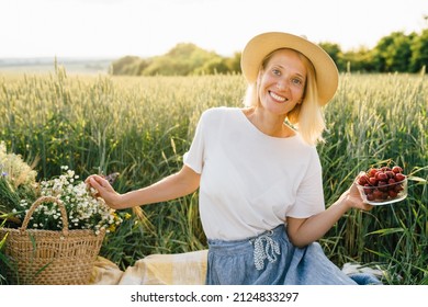 Happy Smiling Mature Woman Relaxing In Picnic In Countryside. Blond Lady In A Wheat Field. Slim Female With Basket Wild Flowers.