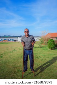 Happy smiling middle aged man playing stilt walking, reminiscing childhood. Adult having fun with child's play. Paraná, Brazil. 