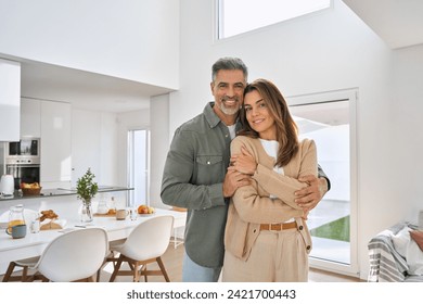 Happy smiling middle aged romantic affectionate couple mature older man and woman hugging standing at home together looking at camera enjoying bonding in modern house living room. Portrait. - Powered by Shutterstock