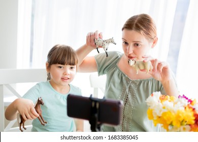 Happy Smiling Mom And Little Child Girl Daughter Enjoy Using Smartphone: Recording Video Infront Of Camera Sitting At The Table. Family Vloggers, Education Baby Blog About Toys Or Animals