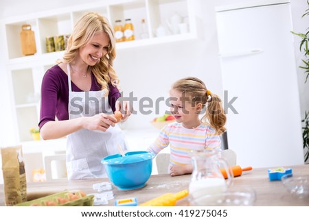 Happy smiling mother and daughter baking cookies