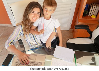 Happy Smiling Mother Sititng At The Desk With Son At Her Lap, Peaceful Mom Using Modern Computer, Work From Home At Quarantine Time, Coronavirus Pandemia Lifestyle, Parenting, Upbringing