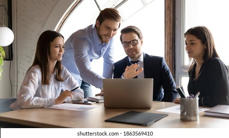 Happy smiling multiethnic group of young employees interns students learn to solve business problems on training course with professional expert coach mentor tutor assistance using modern computer app - Shutterstock ID 1863569410
