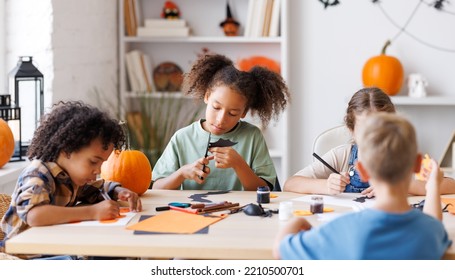 Happy Smiling Multinational Group Of Children  Making Halloween Home Decorations Together, Kids Painting Pumpkins And Making Paper Cuttings