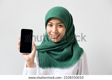 Happy smiling muslim woman showing black smartphone screen