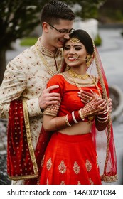 Happy And Smiling Newlyweds. The Young Groom Embraces His Indian Wife On The Street