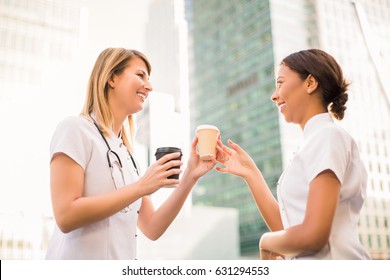 Happy Smiling Nurse Gives Cup Of Coffee Another Smiling Nurse In Time Of A Break, Outdoors