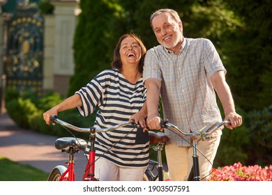Happy smiling old couple with bikes. Outdoor activity and healthy lifestyle concept. Summer garden park background.