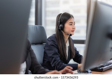 Happy smiling operator asian woman customer service agent with headsets working on computer in a call center, talking with customer for assisting to resolve the problem with her service mind - Shutterstock ID 1573436293