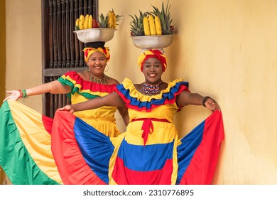 Happy, smiling Palenquera fresh fruit street vendors in the Old Town of Cartagena de Indias, Colombia. Cheerful Afro-Colombian women in traditional clothing, Colombian culture and lifestyle.
