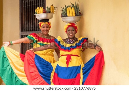 Happy, smiling Palenquera fresh fruit street vendors in the Old Town of Cartagena de Indias, Colombia. Cheerful Afro-Colombian women in traditional clothing, Colombian culture and lifestyle.