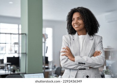 Happy smiling portrait of young African American leader manager, stands confident, crossed arms and looking aside in business office center. Portrait of professional business woman in stylish suit.