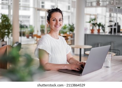 happy smiling remote working woman talking to laptop or notebook in casual outfit sitting on her work desk in her modern loft living room home office having a video chat - Powered by Shutterstock