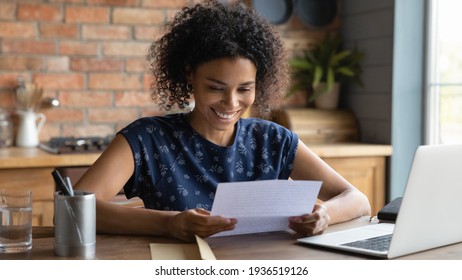 Happy smiling remote working young black female receive postal letter from company office about project report approval. Glad millennial afro american employee reading good news from paper document