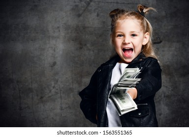 Happy Smiling Rich Kid Girl Millionaire Give And Hold Bundle Of Money Euro Hundreds Dollars Cash Bills In Hand Screaming On Dark Wall Background