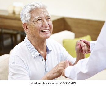 happy and smiling senior asian man in his 80s getting helped by medical worker