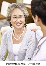 Happy Smiling Senior Asian Woman Talking And Being Comforted By A Female Doctor.