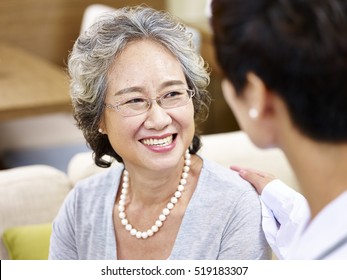 Happy Smiling Senior Asian Woman Talking And Being Comforted By A Female Doctor.