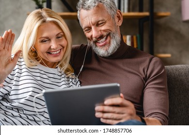 Happy smiling senior couple with digital tablet computer having video call at home - Powered by Shutterstock