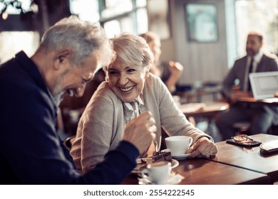 Happy smiling senior couple enjoying coffee in modern cafe