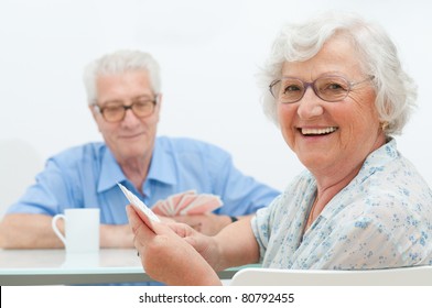 Happy smiling senior couple playing cards together at home - Powered by Shutterstock