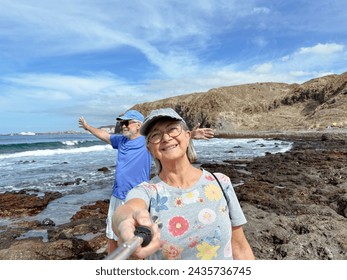 Happy smiling senior couple in retirement enjoying sunny day at sea while taking self portraits together with a smartphone and selfie stick - Powered by Shutterstock