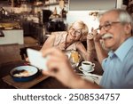 Happy smiling senior couple taking selfie in cozy bistro