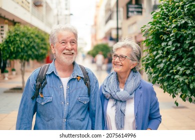 Happy smiling senior couple of tourist walking in the city. Attractive white haired caucasian people