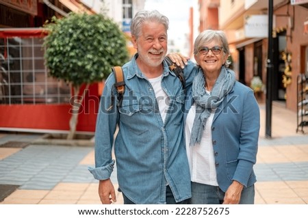 Happy smiling senior couple of tourist walking in the city. Attractive white haired caucasian people enjoying free time or retirement