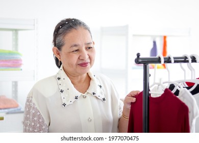 Happy Smiling Senior Elderly Woman Housewife Hanging Clothes Indoor To Dry, Older Asian Female Doing Laundry At Laundry Room, Dried Laundry, Grandma Doing Housework And Cleaning Clothes At House