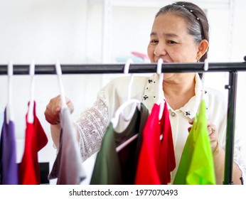 Happy Smiling Senior Elderly Woman Housewife Hanging Clothes Indoor To Dry, Older Asian Female Doing Laundry At Laundry Room, Dried Laundry, Grandma Doing Housework And Cleaning Clothes At House