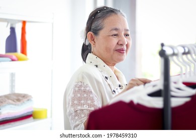 Happy Smiling Senior Elderly Woman Housewife Hanging Clothes Indoor To Dry, Older Asian Female Doing Laundry At Laundry Room, Dried Laundry, Grandma Doing Housework And Cleaning Clothes At House