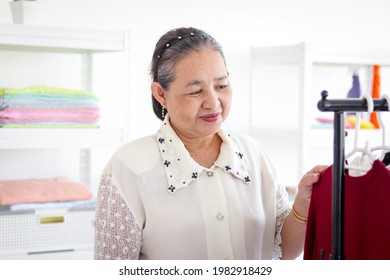 Happy Smiling Senior Elderly Woman Housewife Hanging Clothes Indoor To Dry, Older Asian Female Doing Laundry At Laundry Room, Dried Laundry, Grandma Doing Housework And Cleaning Clothes At House