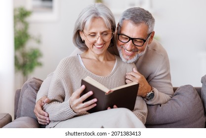 Happy smiling senior family couple in love reading book together, hugging embracing while spending free time at home on retirement, beautiful retired husband and wife enjoying life - Powered by Shutterstock