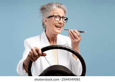 Happy, smiling senior woman, driver wearing formal wear, holding mobile phone, recording audio message, isolated on blue background. Online communication concept - Powered by Shutterstock