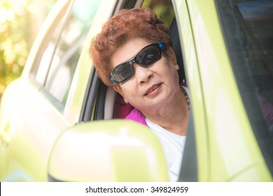 Happy And Smiling Senior Woman Wearing Sunglass In Green Car