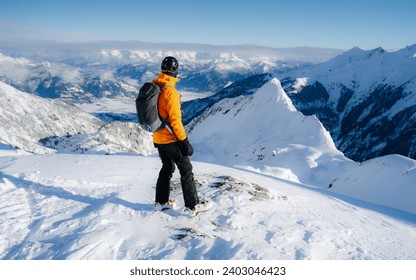 Happy smiling skier during active winter holidays. Man in winter clothing walking in snow and carrying ski on shoulder. Sporty man skiing with copy space of blue sky and snowy mountain. - Powered by Shutterstock