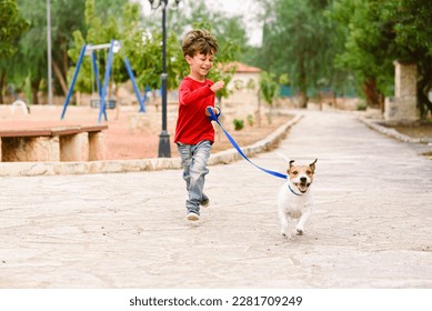 Happy smiling small boy playing and running with his pet dog in park - Powered by Shutterstock