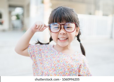 Happy Smiling Smart And Nerd Little Asian Girl In Glasses And Pointing Finger At Brain And Going To School For The First Time.Child With School Kindergarten.Child Development And Education Concept.